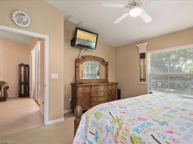 Bedroom featuring baseboards, vaulted ceiling, a ceiling fan, light colored carpet, and light tile patterned flooring