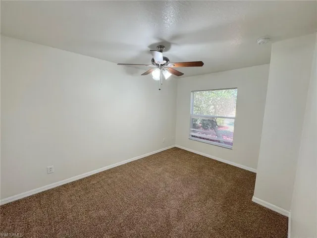 Carpeted spare room with ceiling fan and a textured ceiling