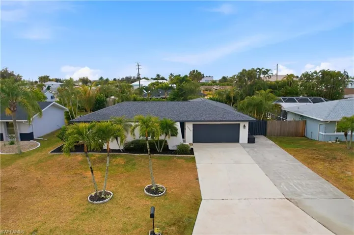 View of front facade with concrete driveway, a front yard, a shingled roof, an attached garage, and stucco siding
