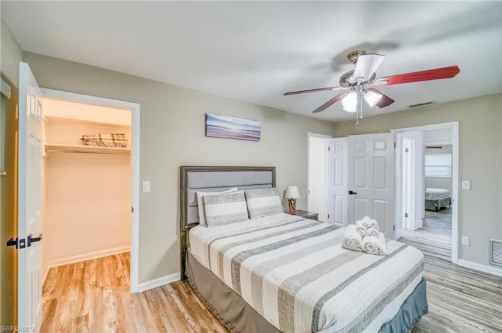 Bedroom with light wood finished floors, a closet, a spacious closet, and baseboards