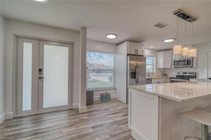 Kitchen featuring stainless steel appliances, light stone countertops, white cabinets, light wood finished floors, and recessed lighting