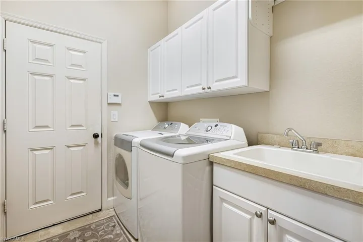 Laundry area leads to Garage, it has sink, cabinets, drying bar, washing machine and clothes dryer