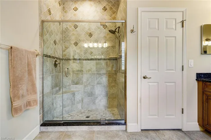 Enclosed shower is tiled to the ceiling and has bench seat