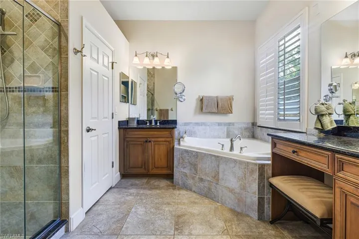 Bathroom with Dual Wooden Vanities with Granite counters, roll out cabinet shelves, a wealth of natural light with Plantation Shutters, and plus walk in shower, large soaking tub and Water Closet.