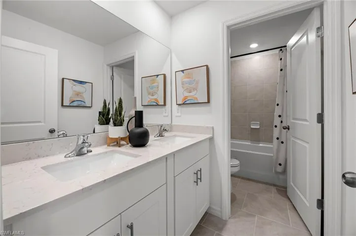 Full bathroom featuring tile patterned floors, double vanity, shower / tub combo with curtain, and a sink