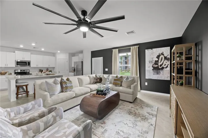 Living area with recessed lighting, light tile patterned floors, visible vents, and a ceiling fan