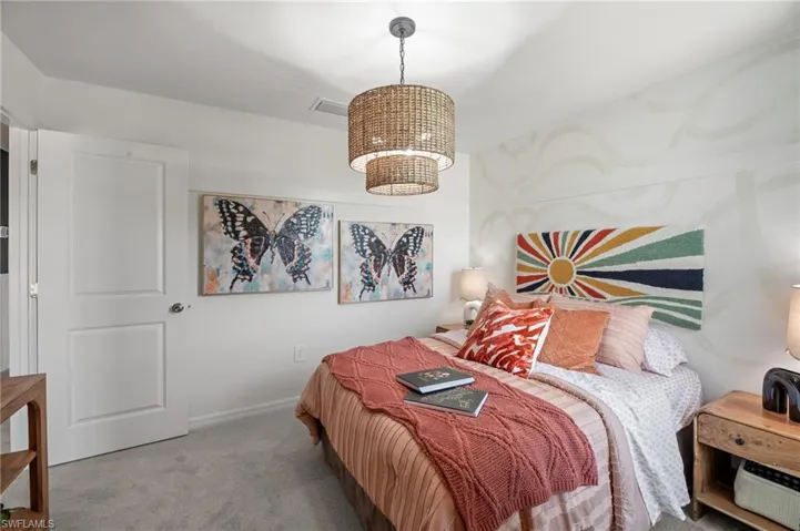 Carpeted bedroom featuring a chandelier and visible vents