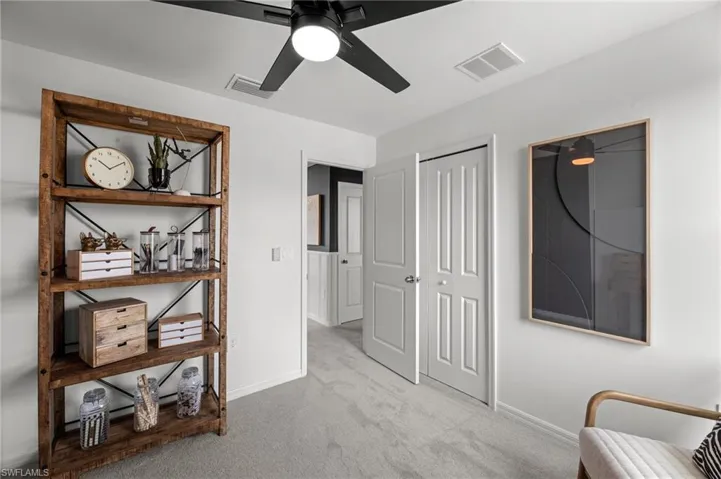 Sitting room with visible vents, carpet floors, baseboards, and ceiling fan