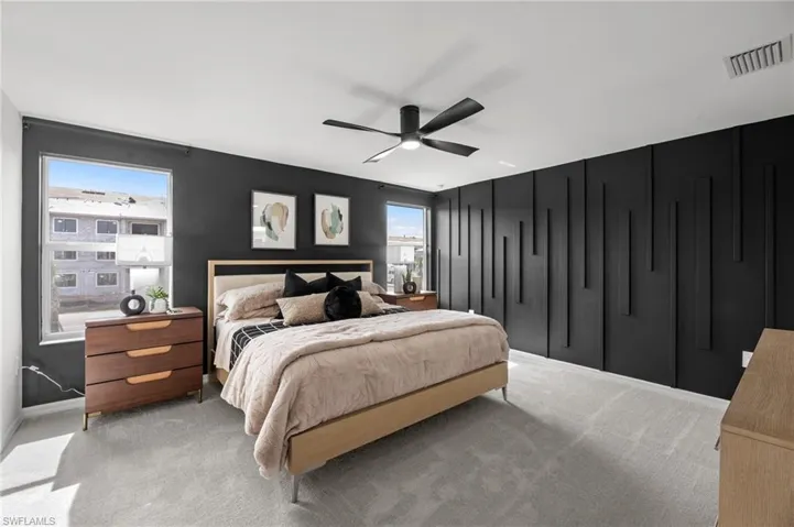 Carpeted bedroom with visible vents, baseboards, and ceiling fan