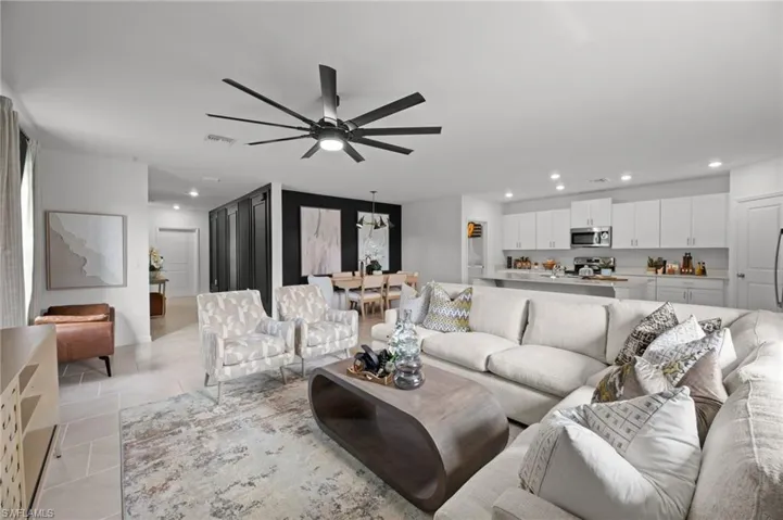Living room with ceiling fan with notable chandelier, light tile patterned flooring, visible vents, and recessed lighting