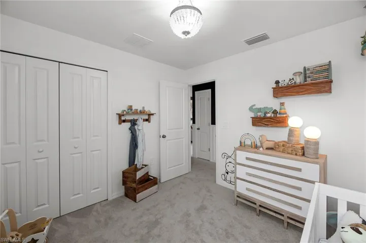 Bedroom with carpet flooring, visible vents, and a closet