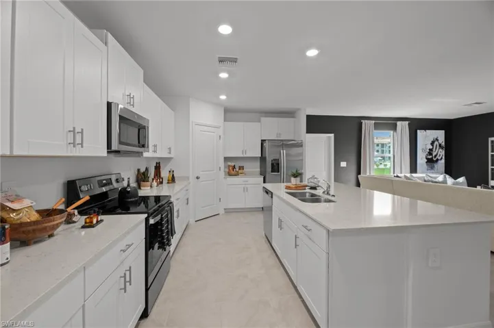 Kitchen featuring recessed lighting, an island with sink, white cabinetry, visible vents, and stainless steel appliances