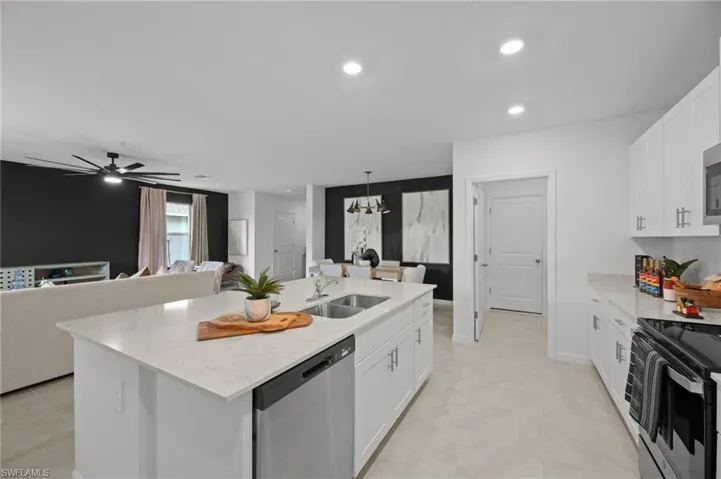 Kitchen featuring a sink, appliances with stainless steel finishes, white cabinetry, and an island with sink