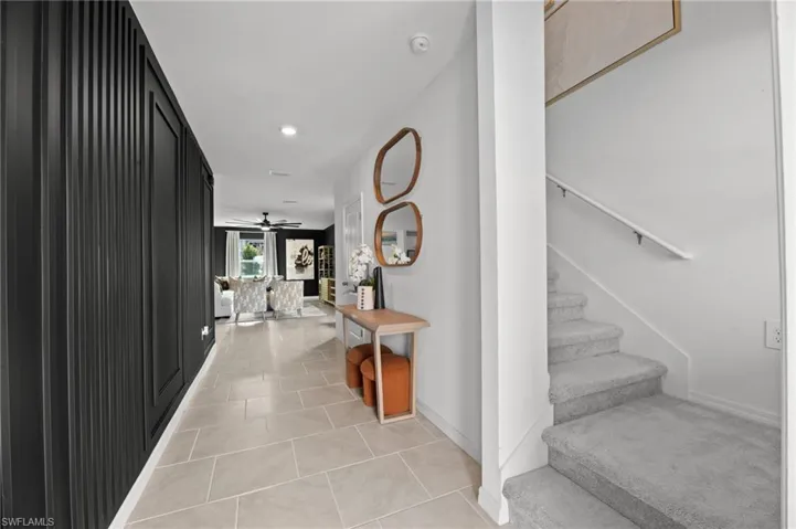 Corridor featuring light tile patterned floors, baseboards, and stairs
