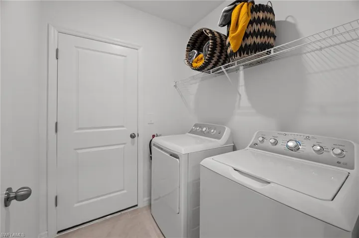 Washroom with light tile patterned floors, laundry area, and washing machine and clothes dryer