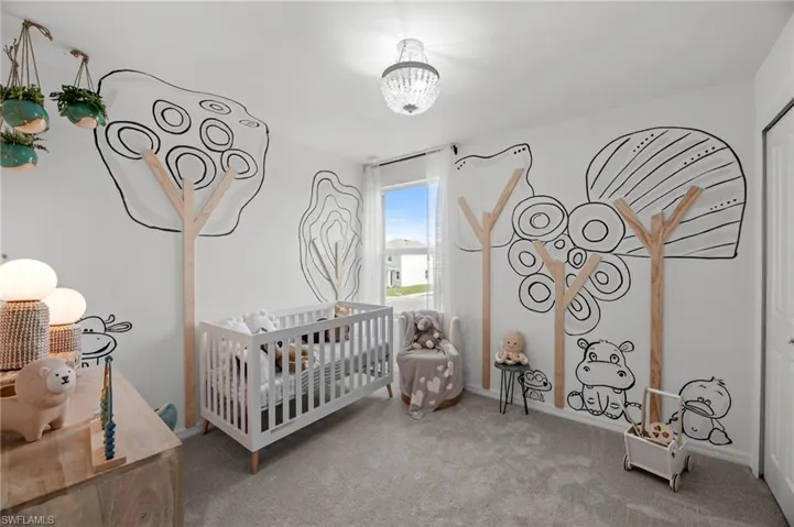 Carpeted bedroom with a notable chandelier and a crib