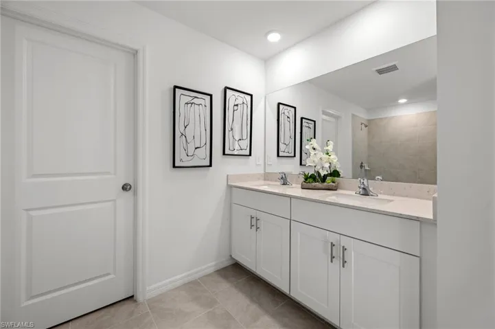 Full bathroom with a sink, visible vents, tiled shower, and double vanity