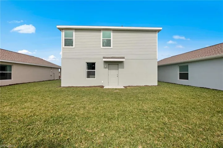 Back of property featuring a lawn and stucco siding