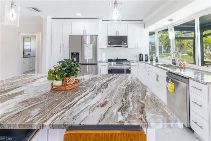 Kitchen featuring crown molding, stainless steel appliances, decorative backsplash, white cabinetry, and recessed lighting