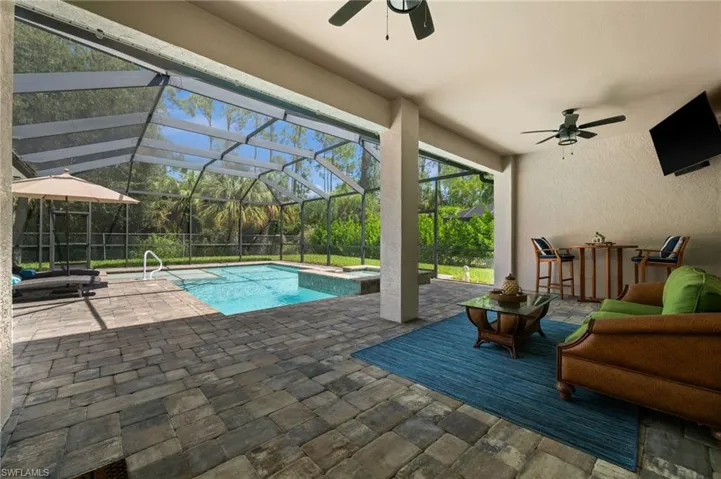 Expansive screened lanai featuring a custom pool with sunshelf and spa, surrounded by generous space for relaxing and entertaining.