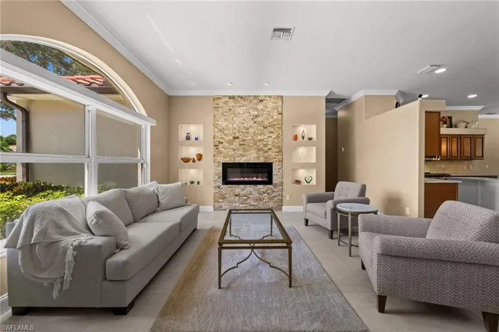 Light-filled living room featuring soaring ceilings, dramatic arched windows, and a striking floor-to-ceiling stone fireplace.