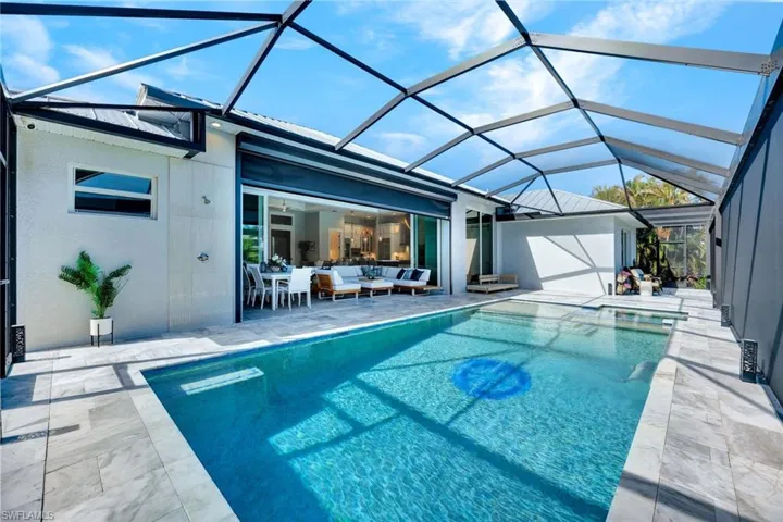View of swimming pool with a sunroom, a patio area, a lanai, a pool with connected hot tub, and an outdoor living space