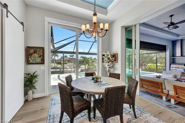 Dining space with a barn door, light wood finished floors, a raised ceiling, and a chandelier