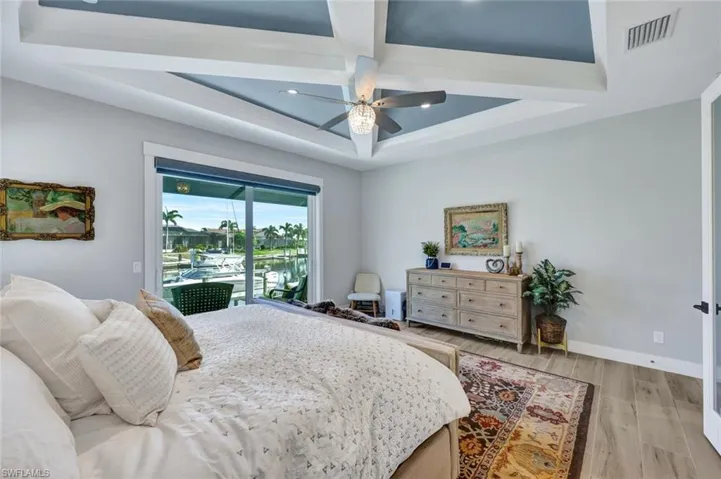 Bedroom featuring light wood-style flooring, access to exterior, coffered ceiling, a ceiling fan, and beamed ceiling