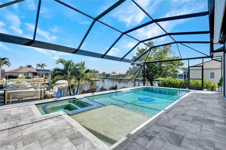 View of pool with a water view, a sunroom, a lanai, a patio area, and a pool with connected hot tub