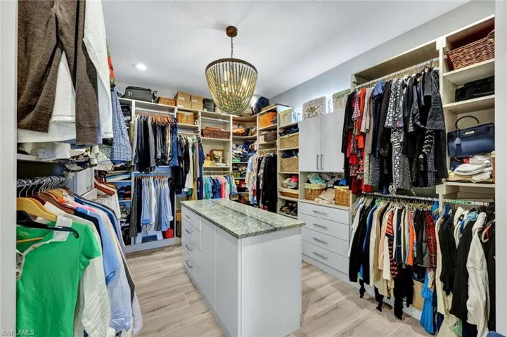 Spacious closet featuring a chandelier and wood finish floors