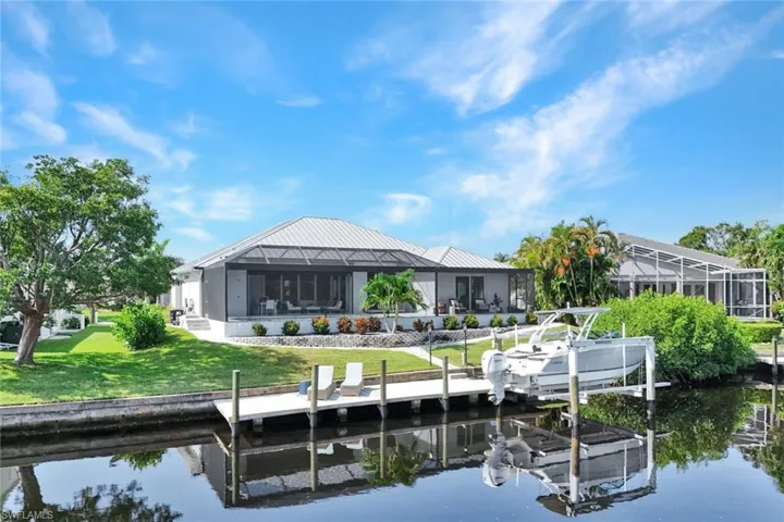Dock area with a water view, a yard, a sunroom, boat lift, and glass enclosure
