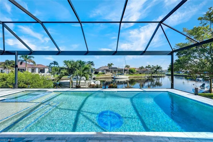 View of swimming pool featuring a sunroom, a water view, a pool with connected hot tub, and a lanai