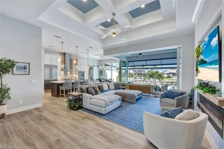 Living area featuring coffered ceiling, a sunroom, beamed ceiling, light wood-type flooring, and a ceiling fan