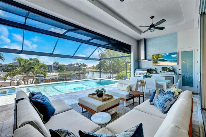 Swimming pool featuring a water view, a sunroom, an outdoor kitchen, and outdoor lounge area