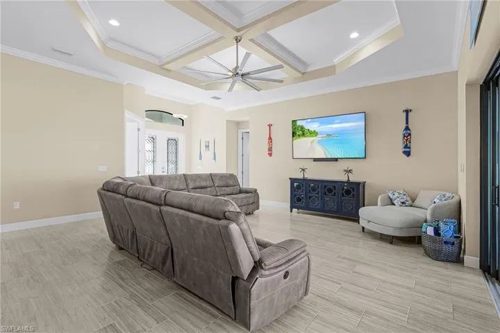 Living room with beamed ceiling, ceiling fan, ornamental molding, and coffered ceiling