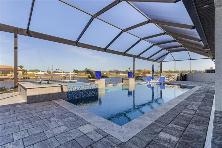 View of swimming pool featuring an in ground hot tub, a patio area, and glass enclosure