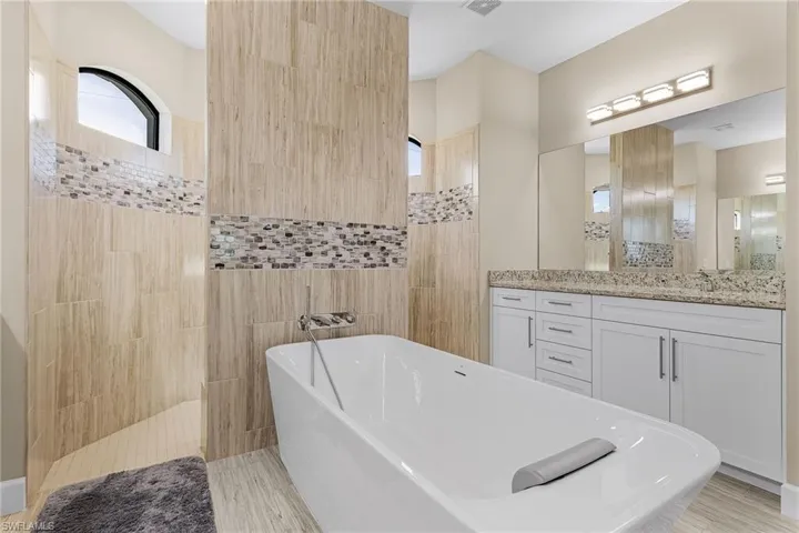 Bathroom with vanity, separate shower and tub, and tile walls