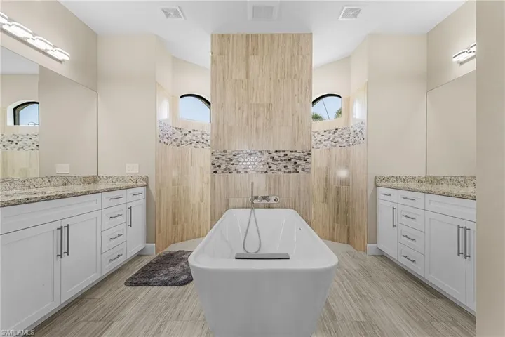 Bathroom featuring a tub to relax in, plenty of natural light, and vanity