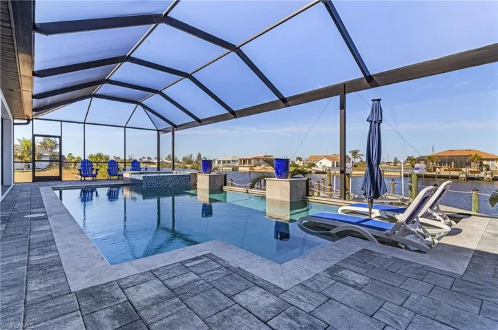 View of pool with a water view, an in ground hot tub, a lanai, and a patio