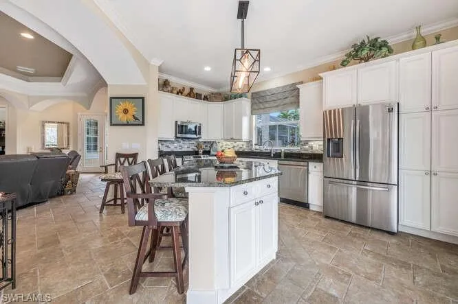 Kitchen featuring decorative backsplash, white cabinets, pendant lighting, and appliances with stainless steel finishes