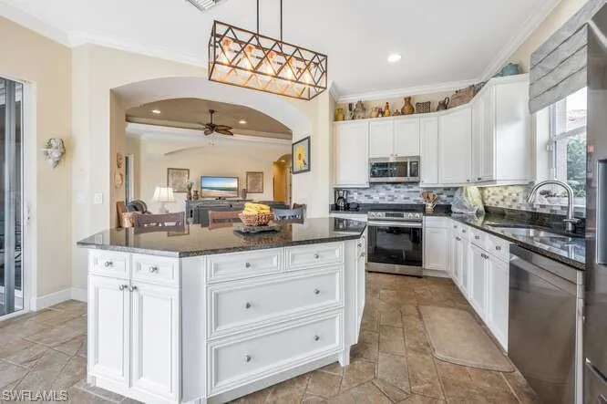 Kitchen featuring crown molding, sink, white cabinetry, a center island, and stainless steel appliances