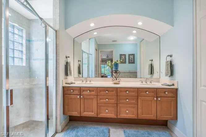 Bathroom with crown molding, a shower with door, and vanity