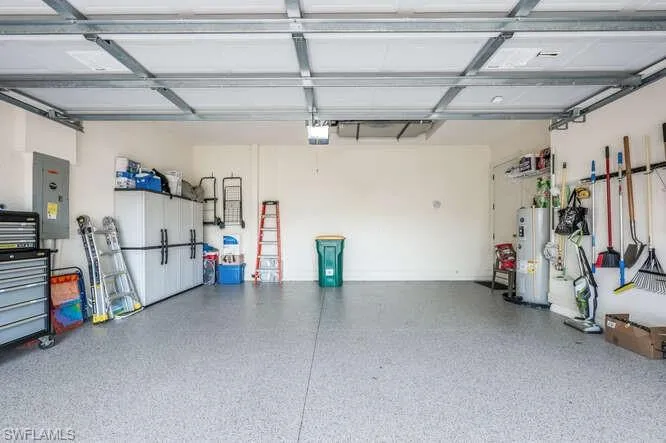 Garage with a garage door opener, electric panel, and water heater
