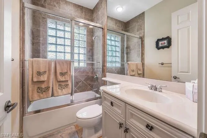 Full bathroom featuring bath / shower combo with glass door, toilet, and vanity