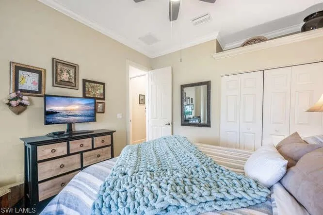 Bedroom with a closet, ceiling fan, and ornamental molding