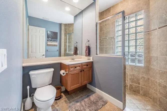 Bathroom with tiled shower, toilet, and vanity