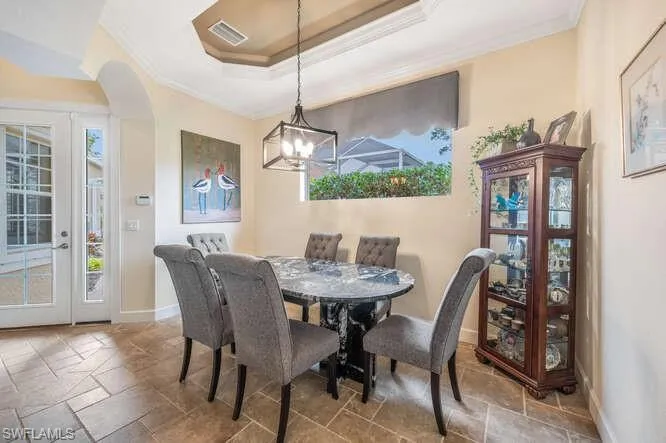 Dining area with a chandelier, a raised ceiling, and crown molding