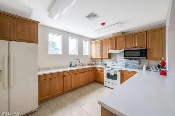Kitchen featuring sink, white appliances, and kitchen peninsula