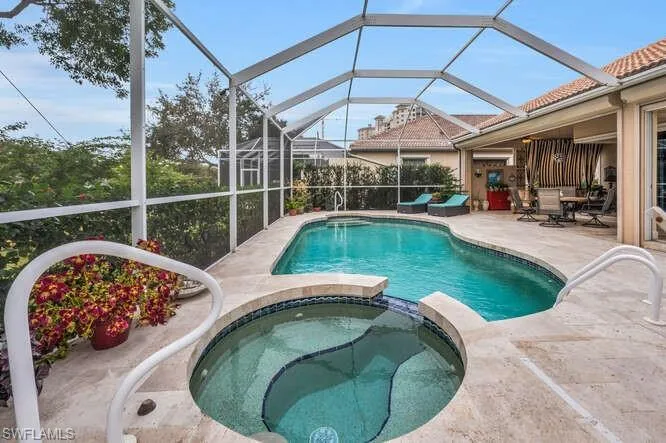 View of pool featuring glass enclosure, an in ground hot tub, and a patio area