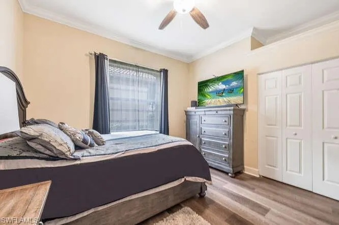 Bedroom with ceiling fan, wood-type flooring, a closet, and ornamental molding